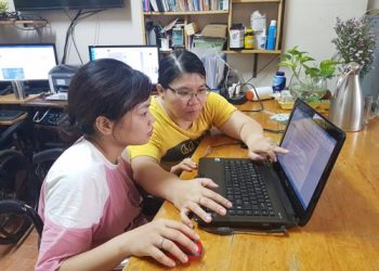 Chị Nguyễn Thị Mỹ Ngọc (phải) hướng dẫn nhân viên thao tác trên máy tính