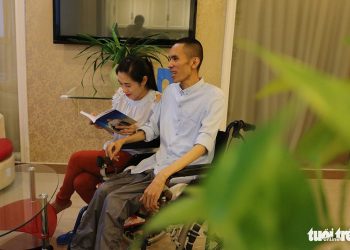 Nguyễn Chánh Tín ngồi xe lăn viết sách